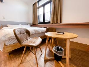 台南小岛民宿的卧室配有1张床、1张桌子和1把椅子