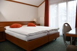采尔马特伊里特酒店的一间卧室配有一张带红色枕头的床和一扇窗户
