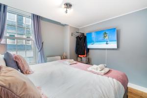 安德沃Central Apartment With 55” Smart TV+Netflix的卧室配有一张大床,墙上配有电视