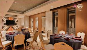 达卡Best Western PLUS Maya - Luxury Collection Hotel的宴会厅配有桌椅和电视。