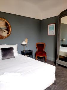 比亚里茨Saint Charles Hôtel & Coliving Biarritz的卧室配有白色的床和红色椅子