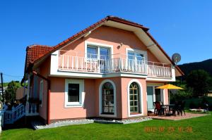 贝谢诺瓦Vila Deluxe & Apartmány Riviéra Liptov Bešeňová的粉红色的房子设有阳台和桌子