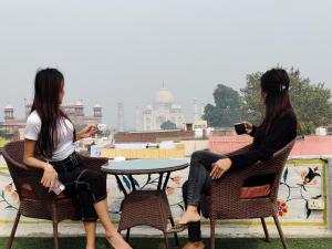 阿格拉Joey's Hostel Agra的两个女人坐在屋顶的桌子上