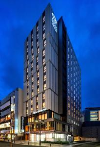 东京DEL style Ikebukuro Higashiguchi by Daiwa Roynet Hotel的一座高大的建筑,旁边有一个标志