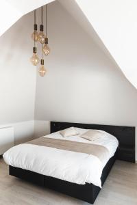 泽德尔海姆Salons Denotter的一间卧室配有一张带白色墙壁和灯光的床