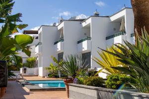 卡门港Apartamentos La Tegala的一座白色的大建筑,设有游泳池和植物