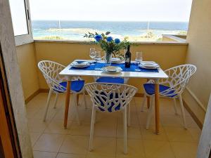 奥特朗托Bilocale Punta Rosa - Fronte Spiaggia的一间带桌椅和窗户的用餐室