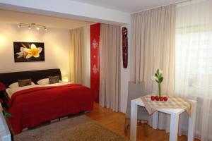 巴特阿巴赫Parkresidenz Hotel Garni的一间卧室配有红色的床和一张带花朵的桌子