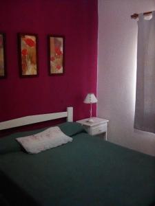 康考迪亚Cabañas de Ayui的一间卧室设有绿色的床和粉红色的墙壁