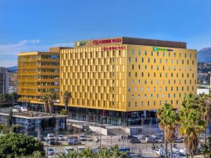 尼斯Holiday Inn Express - Nice - Grand Arenas, an IHG Hotel的停车场里一座黄色的大建筑