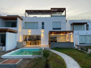 帕拉卡斯Casa en Nuevo Paracas的一座白色的房子,前面设有一个游泳池