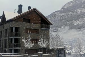贝纳斯克Pleta del Mon Atico的山前有雪的建筑