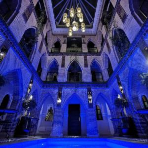 马拉喀什Riad Challa Hotel & Spa的一座拥有蓝色灯光的建筑中的室内游泳池