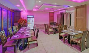 兰奇Treebo Trend Archie Regency的餐厅设有木桌、椅子和紫色照明