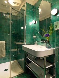 巴黎Le Katorze Hôtel的绿色瓷砖浴室设有水槽和淋浴