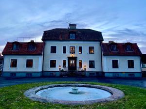 延雪平Tokeryds Herrgård的一座大白色房子,在院子里设有一个喷泉