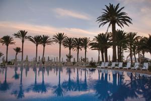 科拉雷侯Hotel Riu Palace Tres Islas的一个带棕榈树和躺椅的游泳池