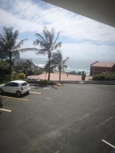 乌姆德洛蒂106 Umdloti Resort的停泊在靠近海洋的停车场的汽车
