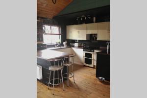 金斯林Norfolk Cabin的一间厨房,配有白色橱柜和一个带凳子的岛屿