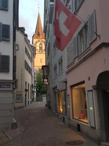 苏黎世Signature Bijou的大楼上带有钟楼和旗帜的街道