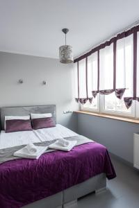 华沙Magnetic apartment Jerozolimskie A的一间卧室配有一张带紫色床单和窗户的床。
