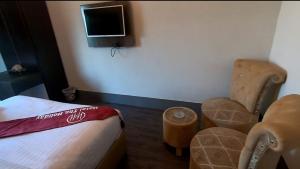 拉合尔Hotel The Holiday的一间带床和两把椅子的房间以及一台电视
