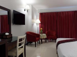 芭堤雅市中心芭堤雅蓝天酒店的酒店客房带一张床、一张桌子和椅子