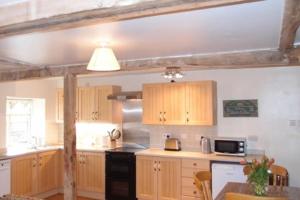 克雷文阿姆斯Upper Heath Farm - Stable Cottage的厨房配有木制橱柜和黑炉。