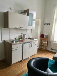 格赖夫斯瓦尔德Apartment Schloss Benrath的厨房配有白色橱柜、水槽和沙发。