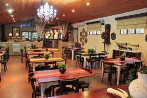 赫卢赫卢韦Emdoneni Lodge的一间带桌椅和吊灯的餐厅