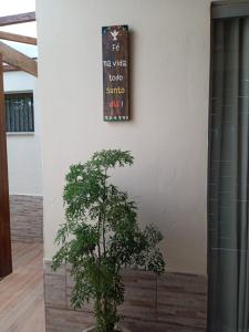 瓦尔任阿Suítes da Rô - hospedaria familiar diária e temporada的围墙旁的植物,有标志