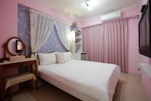 台中市RaRa 旅宿的卧室配有白色的床和粉红色的墙壁