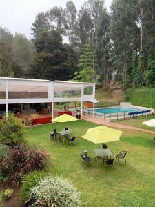 维纳德马Hotel Bosque de Reñaca的院子里一组桌子和黄伞