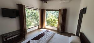 提喀迪Coffee and Pepper Plantation Homestay的一间卧室设有一张床和两个大窗户