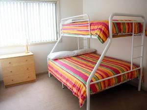 特里格尔Family Beach Retreat in Lovely Terrigal Home的一间卧室配有一张双层床和色彩缤纷的毯子