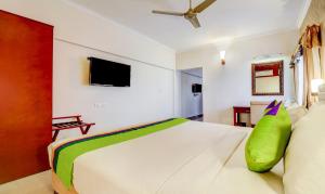 根尼亚古马里RR INN Group Of Hotels的卧室配有一张带绿色枕头的大型白色床