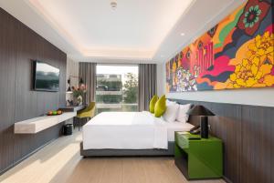 曼谷Maitria Hotel Rama 9 Bangkok - A Chatrium Collection的卧室配有白色的床和墙上的大画作