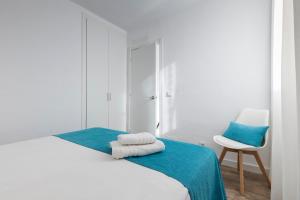 马翁Apartamentos Playa Canutells的白色卧室配有床和椅子