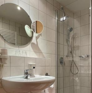 金茨堡Hotel Bettina garni的浴室配有盥洗盆和带镜子的淋浴