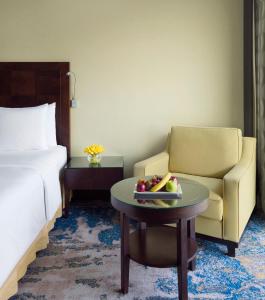 吉达吉达皇冠假日酒店的酒店客房设有椅子和一张桌子,还有一碗水果