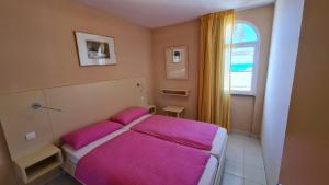 库拉海滩库拉索尔公寓酒店的一间卧室配有一张带粉色床单的床和一扇窗户。