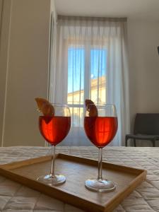 卡梅拉诺Affittacamere Le Grotte - Le Grotte Rooms & Apartments的床上木托盘上放两杯葡萄酒