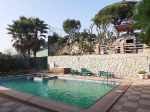 San Fausto de CampcentellasHabitaciones en Villa Coliving Casa Rural的一个带绿色椅子和石墙的游泳池
