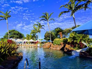 科洛阿ALOHA - Poipu Beach Vacation Condo的棕榈树度假村的游泳池