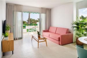 科斯塔特吉塞Nazaret Apartments的客厅配有粉红色的沙发和桌子