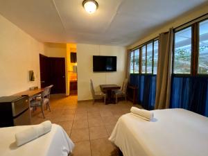 圣萨尔瓦多Morrison Hotel de la Escalon的酒店客房设有两张床、一张桌子和电视。