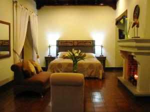 危地马拉安地瓜卡萨圣罗萨精品酒店的一间卧室配有一张床、一把椅子和一个壁炉