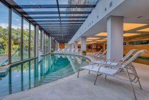 格拉玛多Wyndham Gramado Termas Resort & Spa的室内游泳池设有椅子和窗户