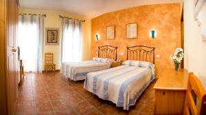 La Zarza埃尔艾里罗乡村酒店的酒店客房设有两张床和一张桌子。