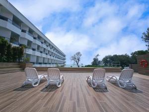 波德申Pacific Regency Beach Resort, Port Dickson的坐在大楼前甲板上的三把椅子